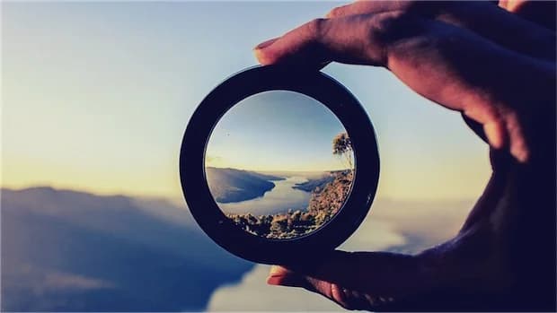 A person standing on a mountain peak looking out at the horizon, symbolizing a long-term vision.